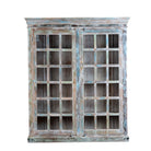 White background image of a reclaimed wood display cabinet Amara with distressed turquoise finish and glass-panelled doors. Sustainable living room furniture and vintage furniture piece with spacious shelving and authentic patina.
