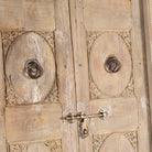 Close up image of a antique Indian door Amaya made of reclaimed teak with brass fittings, hand-carved details, extended frame, usable as entrance or vintage wall panels, 161 × 20 × 250 cm.