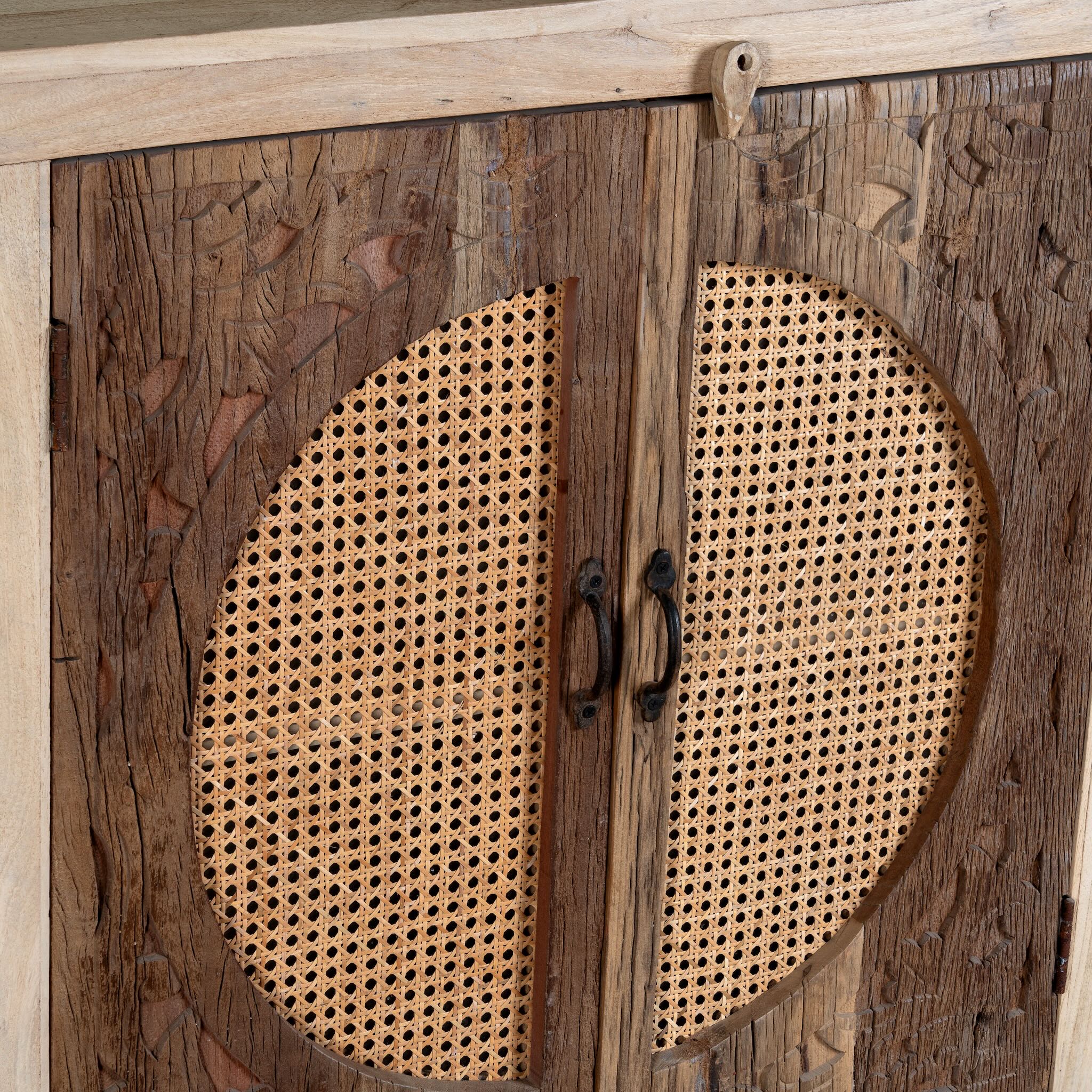 Close up image of a reclaimed wood sideboard Amruta with three drawers and rattan-inlay cabinet doors in a circular design. A piece of sustainable furniture blending rustic wood textures and handcrafted detail.