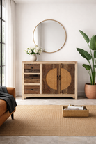 Lifestyle imagination of a reclaimed wood sideboard Amruta with three drawers and rattan-inlay cabinet doors in a circular design. A piece of sustainable furniture blending rustic wood textures and handcrafted detail.