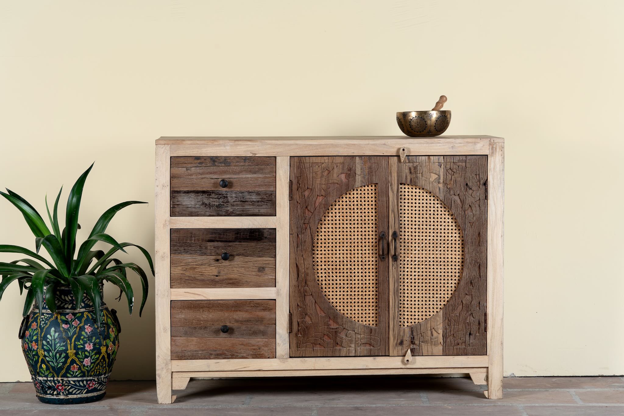 Reclaimed wood sideboard Amruta with three drawers and rattan-inlay cabinet doors in a circular design. A piece of sustainable furniture blending rustic wood textures and handcrafted detail.