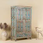 Side angle image of a hand painted wooden furniture cabinet with floral motifs, reclaimed teak artisanal furniture in Mediterranean style, 95 × 40 × 152 cm.
