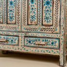 Close up image of the leg part of a hand painted wooden furniture cabinet with floral motifs, reclaimed teak artisanal furniture in Mediterranean style, 95 × 40 × 152 cm.