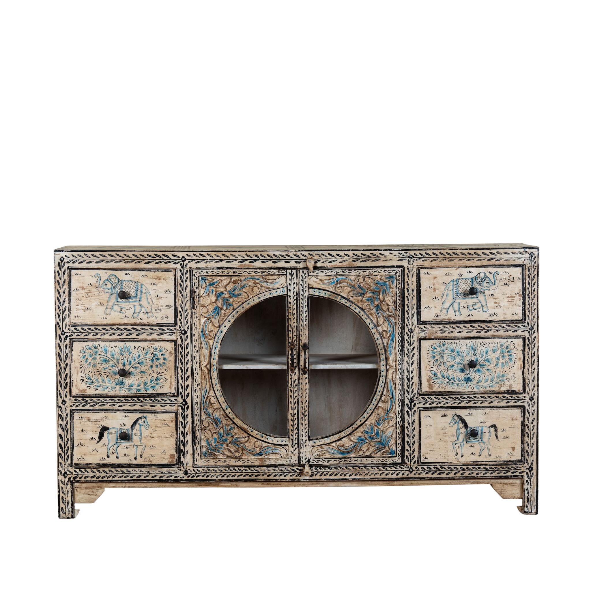 White background image of a hand-painted sideboard Anaya made from reclaimed wood with six drawers and two glass doors, featuring detailed animal and floral motifs. A sustainable piece of boho-style artisanal furniture with colourful heritage design.