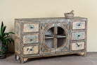 Side angle image of a hand-painted sideboard Anaya made from reclaimed wood with six drawers and two glass doors, featuring detailed animal and floral motifs. A sustainable piece of boho-style artisanal furniture with colourful heritage design.