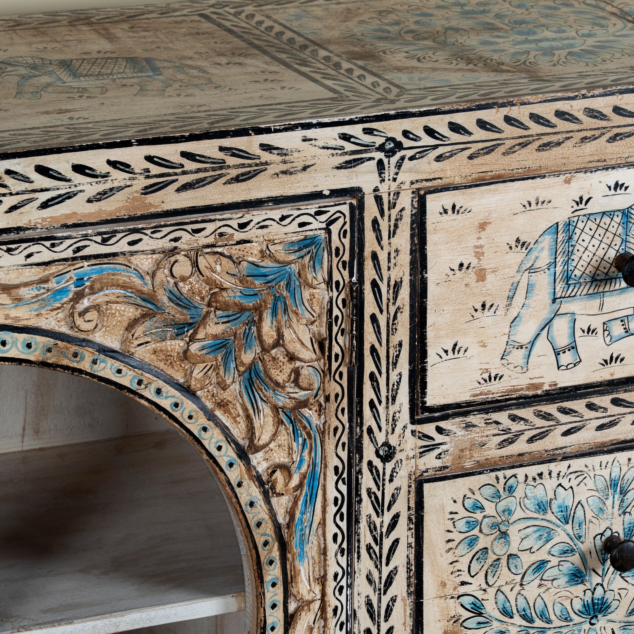 Close up image of a hand-painted sideboard Anaya made from reclaimed wood with six drawers and two glass doors, featuring detailed animal and floral motifs. A sustainable piece of boho-style artisanal furniture with colourful heritage design.