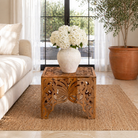 Lifestyle image of a square hand carved coffee table made from solid mango wood with intricate detailing; compact and rustic, 50 × 50 × 40 cm.