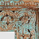 Close up image of a carved mango wood mirror Anila with turquoise finish and hand-carved floral motifs. A bold and colorful addition to vintage home decor and Indian-inspired interiors.
