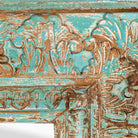 Close up image of a carved mango wood mirror Animisha with turquoise finish and floral hand-carving. A statement piece for vintage home decor and Indian-inspired interiors.