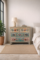 Lifestyle imagination of a hand-painted chest of drawers Anjana made from reclaimed wood, featuring four drawers with floral motifs in vibrant colours. A standout piece of sustainable furniture and painted wooden artistry.