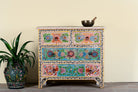 Hand-painted chest of drawers Anjana made from reclaimed wood, featuring four drawers with floral motifs in vibrant colours. A standout piece of sustainable furniture and painted wooden artistry.