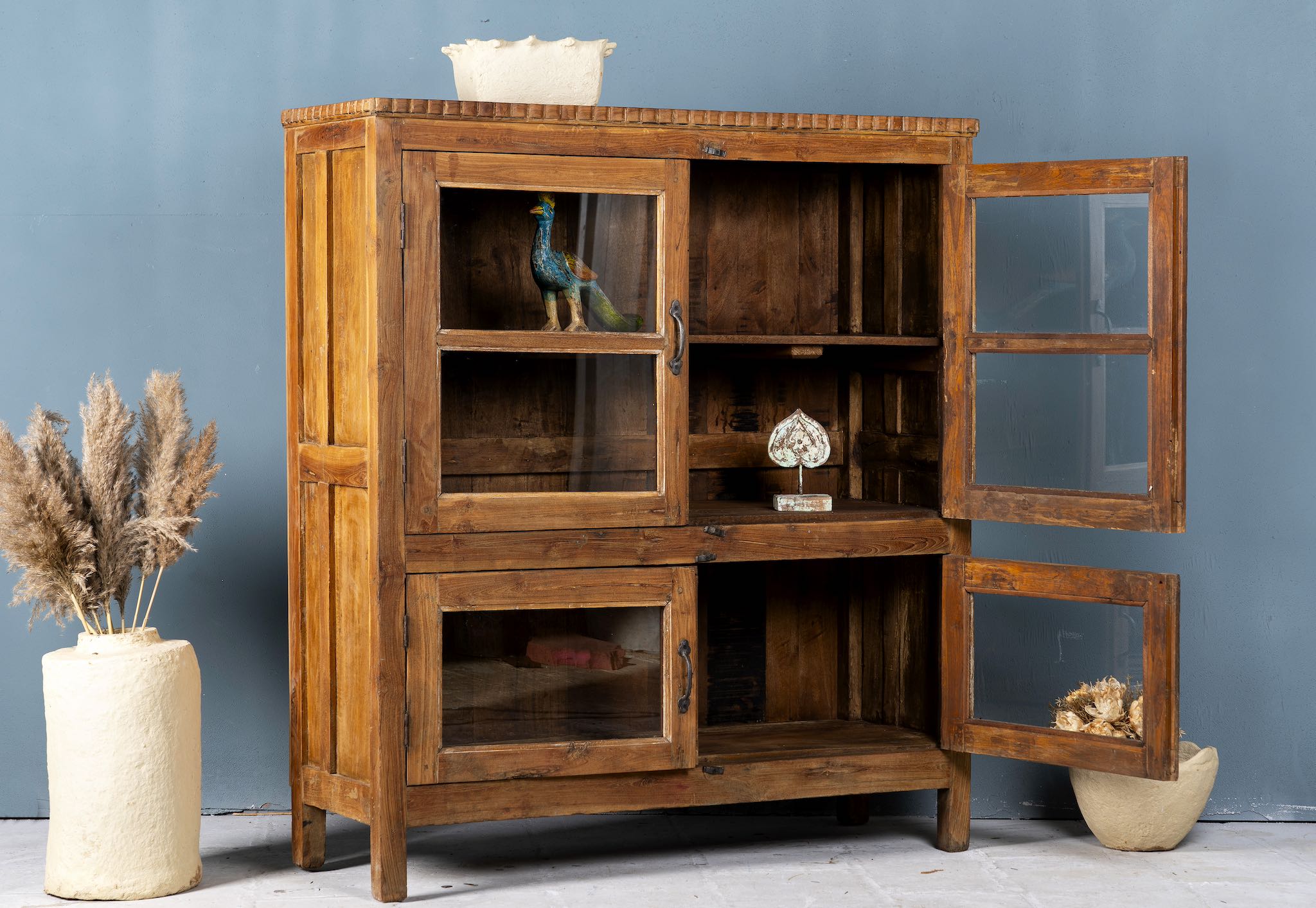 Side angle image with open doors of a reclaimed teak wood display cabinet with four glass-panelled doors – wooden showcase cabinet crafted as sustainable furniture with timeless appeal.