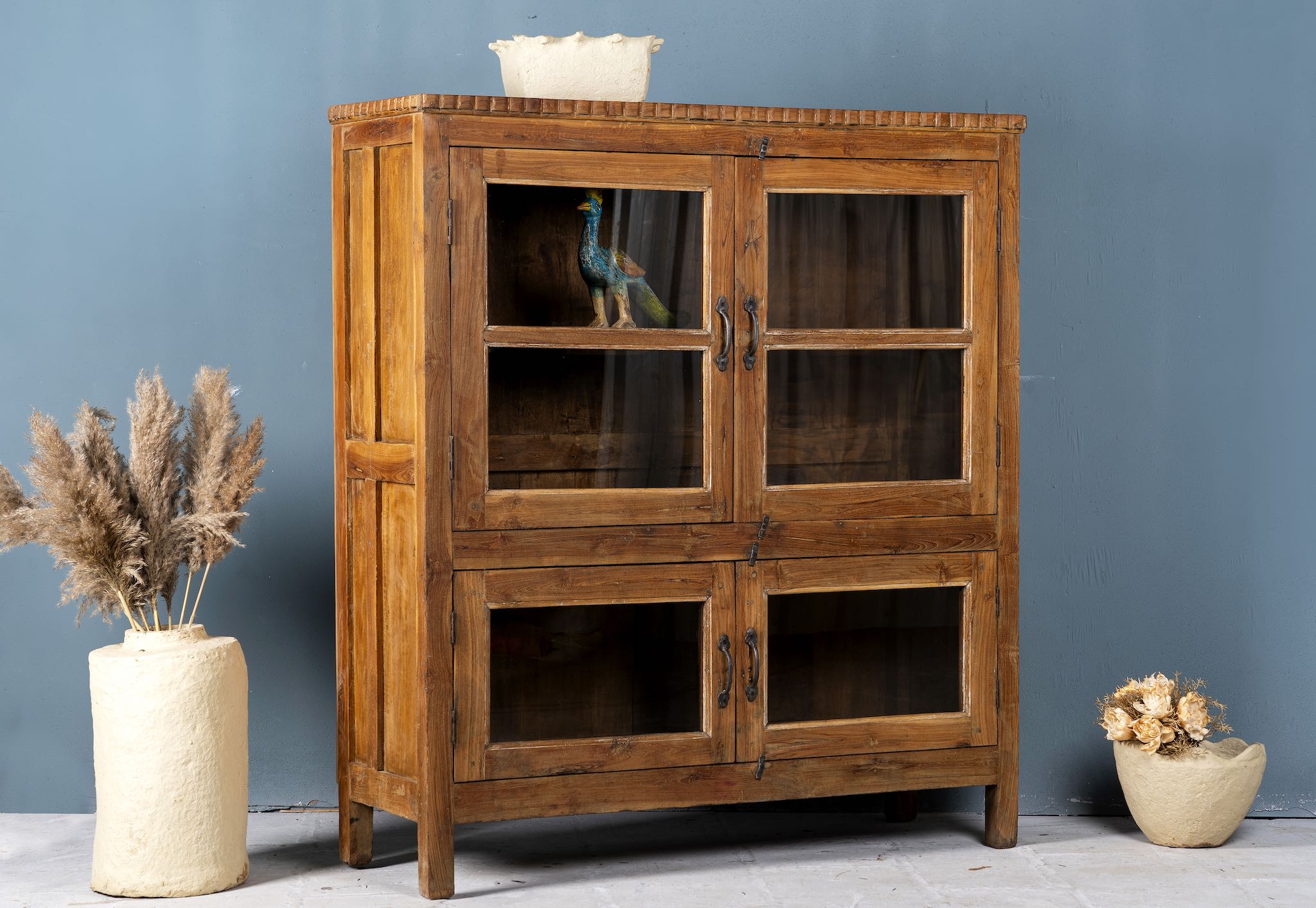 Side angle image with open doors of a reclaimed teak wood display cabinet with four glass-panelled doors – wooden showcase cabinet crafted as sustainable furniture with timeless appeal.