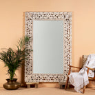 Carved wood mirror Antaka made from solid mango wood with hand-carved frame. A unique piece of living room furniture and boho wall décor that adds light and rustic elegance to any space.