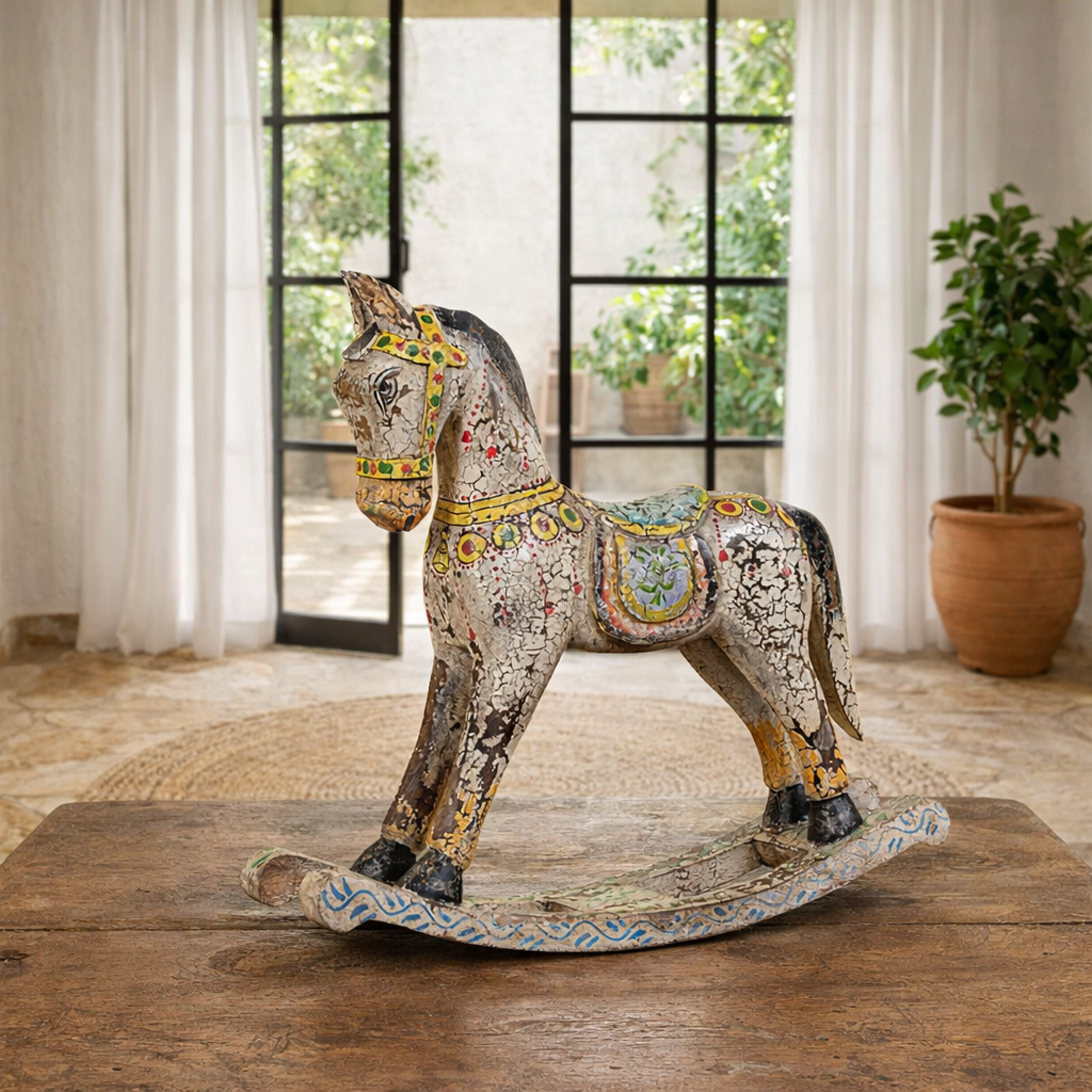 Lifestyle image of a of a colourful hand-painted wooden rocking horses with ornate saddle patterns, crafted in India. Unique bohemian interior décor accents made from solid wood, perfect for shelves or sideboards.