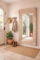 Lifestyle imagination of a carved wood mirror Anushara made from hand-carved mango wood with floral motifs and distressed finish. A bold piece of living room furniture ideal for boho and coastal-inspired spaces.