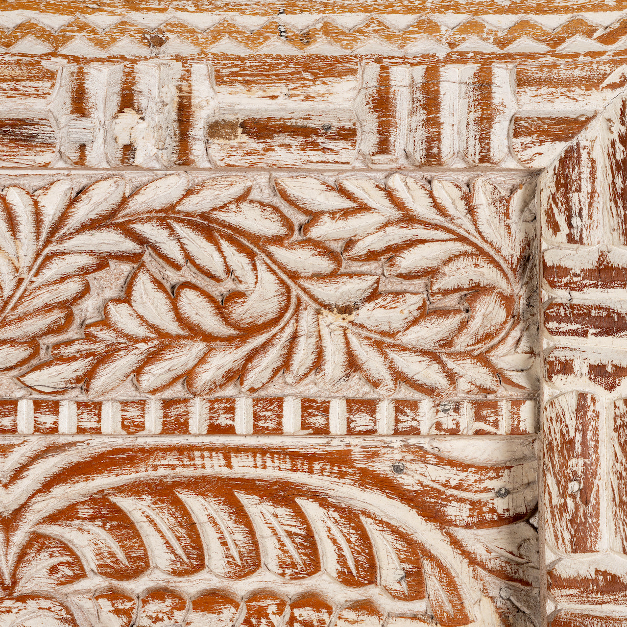 Close up image of a carved wood mirror Anushara made from hand-carved mango wood with floral motifs and distressed finish. A bold piece of living room furniture ideal for boho and coastal-inspired spaces.