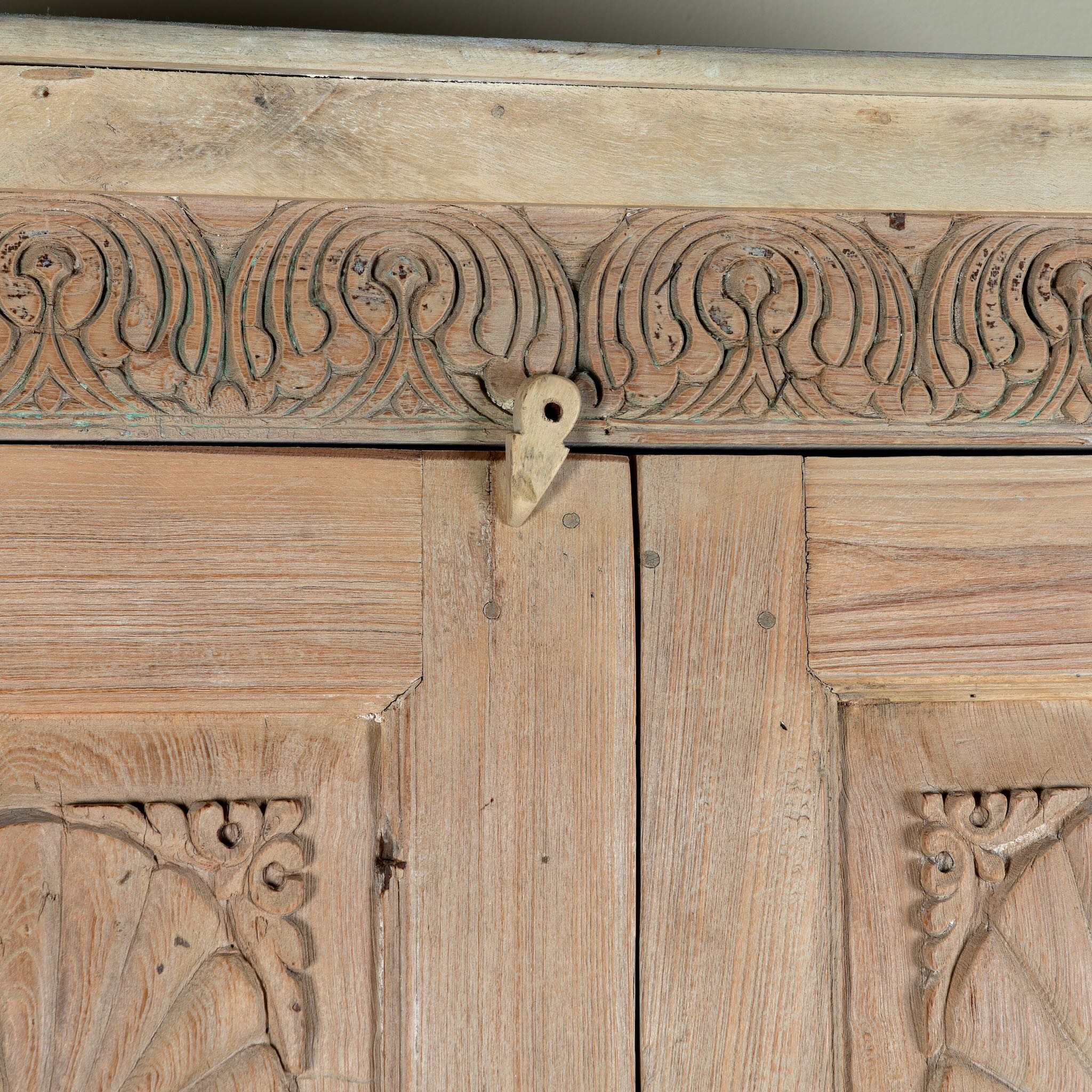 Close up image of a reclaimed teak wood cabinet Anwika featuring a tall Mediterranean-style frame with hand-carved antique Indian doors. A unique piece of Indian furniture offering character-rich storage and timeless design.