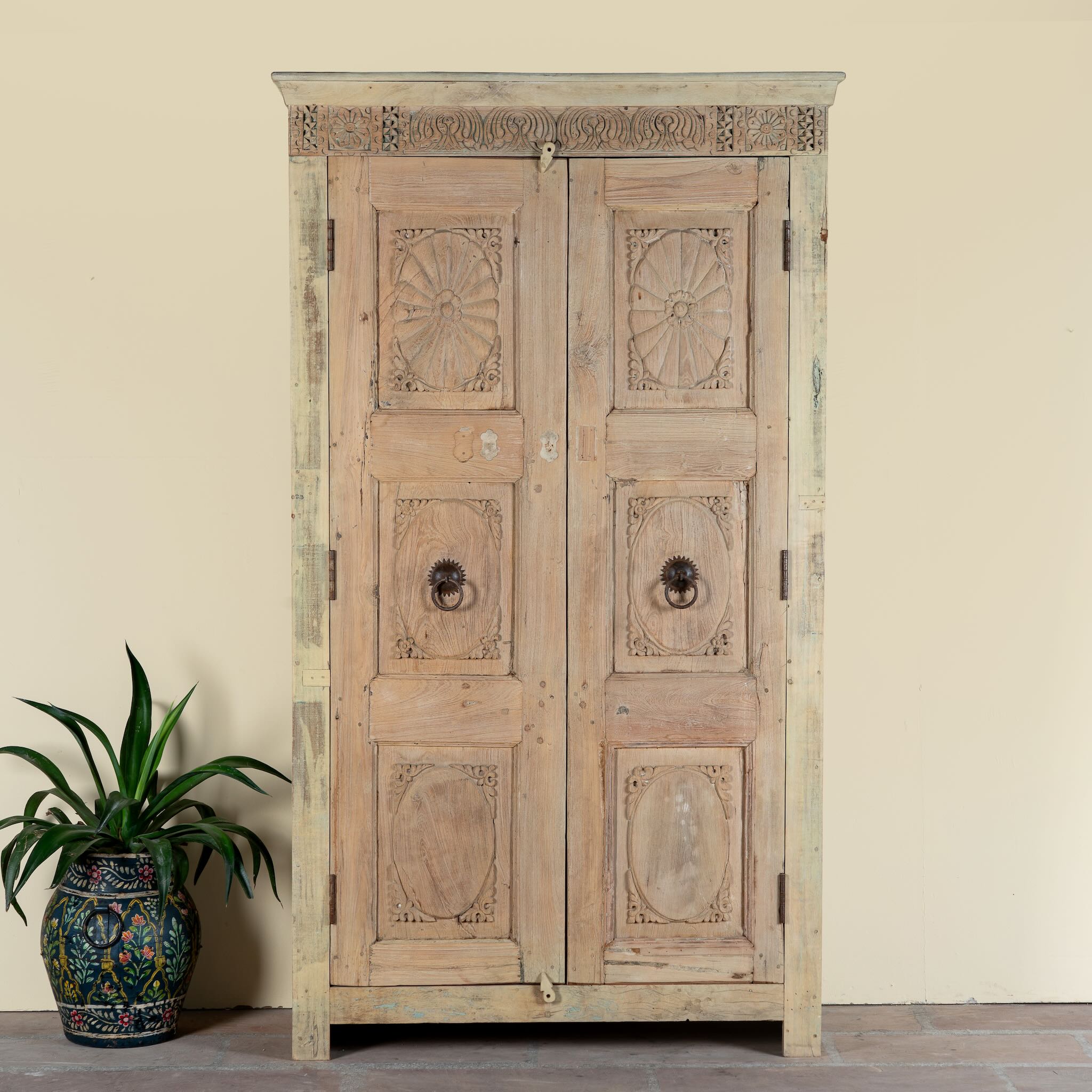 Reclaimed teak wood cabinet Anwika featuring a tall Mediterranean-style frame with hand-carved antique Indian doors. A unique piece of Indian furniture offering character-rich storage and timeless design.