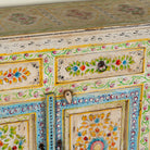 Close up image of a hand-painted reclaimed wood cabinet Anwita in Mediterranean Boho style with floral motifs, four drawers, and four doors. A colourful and sustainable statement piece for boho chic living room décor.