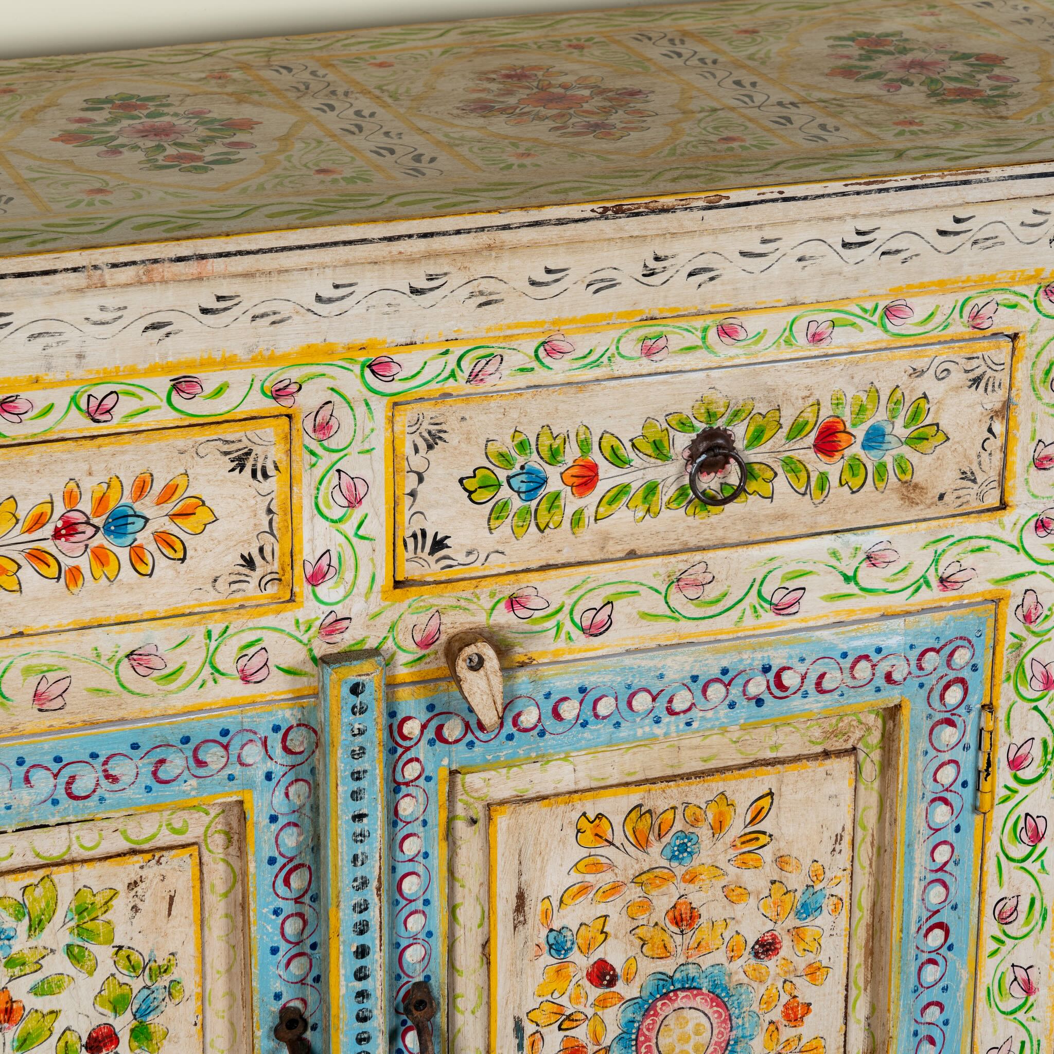 Close up image of a hand-painted reclaimed wood cabinet Anwita in Mediterranean Boho style with floral motifs, four drawers, and four doors. A colourful and sustainable statement piece for boho chic living room décor.