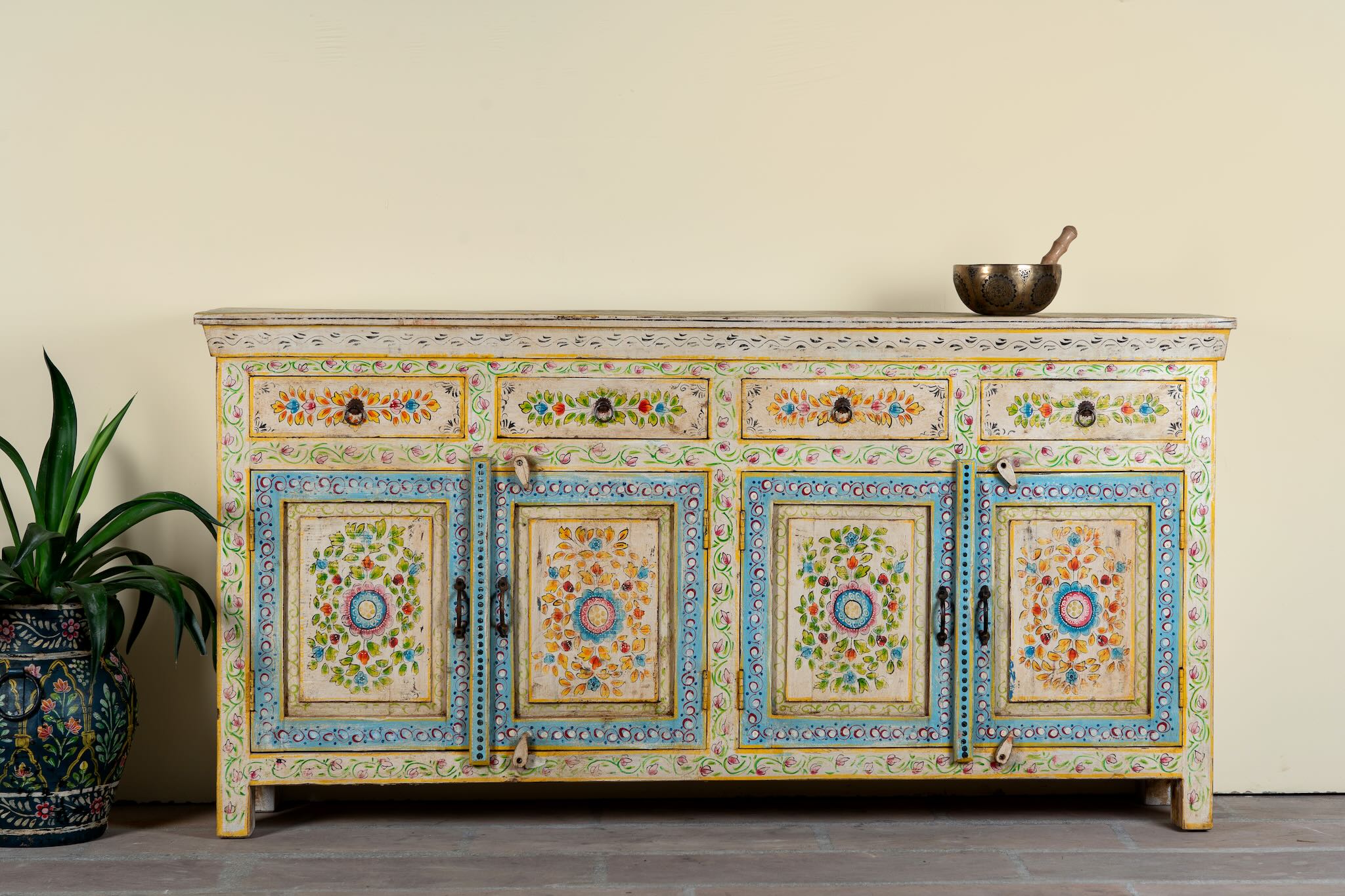 Hand-painted reclaimed wood cabinet Anwita in Mediterranean Boho style with floral motifs, four drawers, and four doors. A colourful and sustainable statement piece for boho chic living room décor.