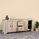 Wooden sandblasted sideboard Ibiza style with storage compartments and a plant on a beige wall background