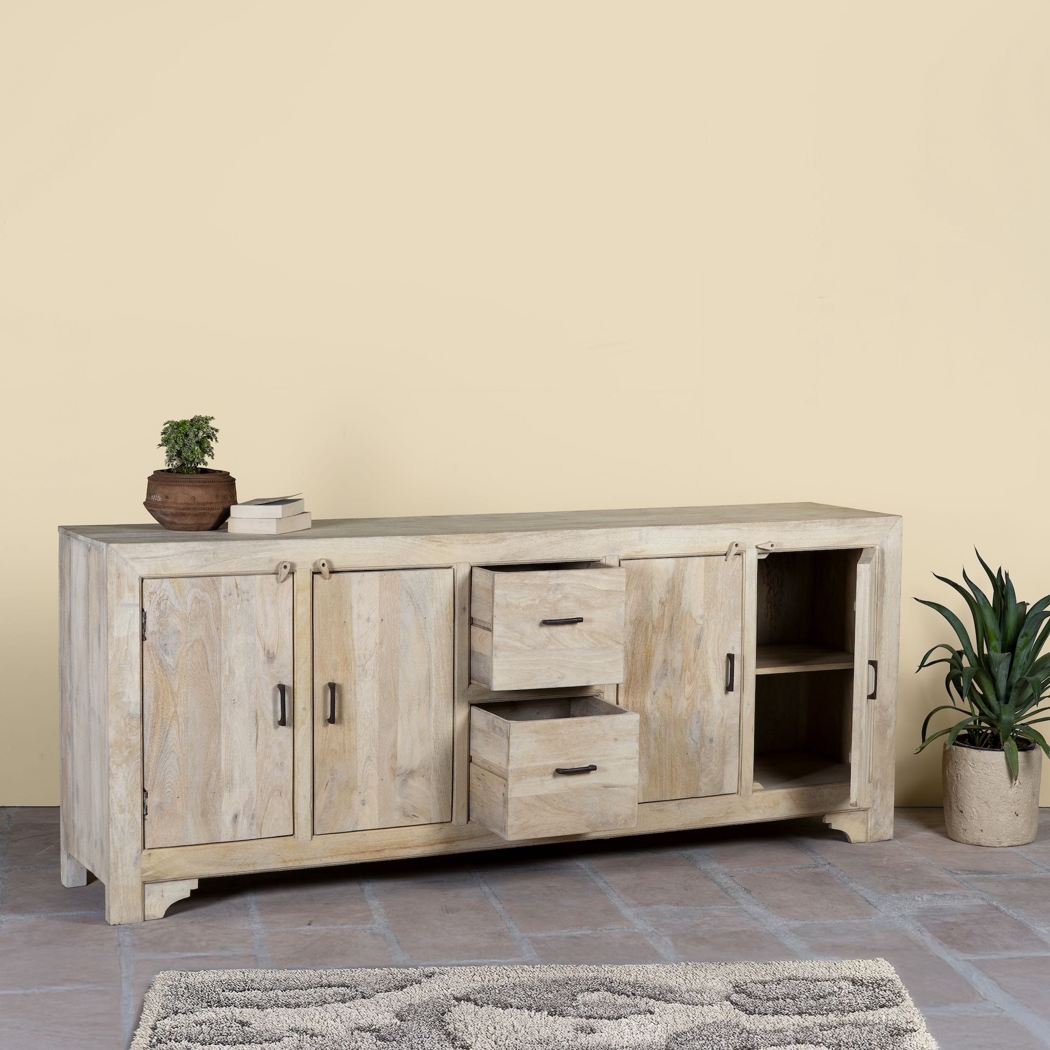 Wooden sandblasted sideboard Ibiza style with storage compartments and a plant on a beige wall background