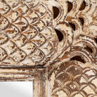 Close up image of a carved mango wood mirror Apasmara in white-washed finish with hand-carved floral details. A handcrafted Indian furniture piece ideal for vintage home decor and boho interiors.