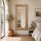 Lifestyle image of a carved mango wood mirror Apsara in white-washed finish with hand-carved floral design. A tall, artisan-crafted piece of Indian furniture ideal for vintage home decor and bohemian interiors.
