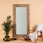 Carved mango wood mirror Apsara in white-washed finish with hand-carved floral design. A tall, artisan-crafted piece of Indian furniture ideal for vintage home decor and bohemian interiors.
