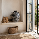 Lifestyle image of a hand-painted clay vase with vintage distressed charcoal finish, sculptural side handles and decorative rivet details, 30x38cm.