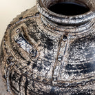 Close up image of a hand-painted clay vase with vintage distressed charcoal finish, sculptural side handles and decorative rivet details, 30x38cm.