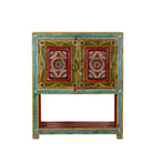 White background image of a small hand-painted console made from reclaimed wood, featuring vibrant decorative motifs in red, green, blue, and gold on double doors, with intricate floral and geometric patterns and a lower open shelf for added display.

