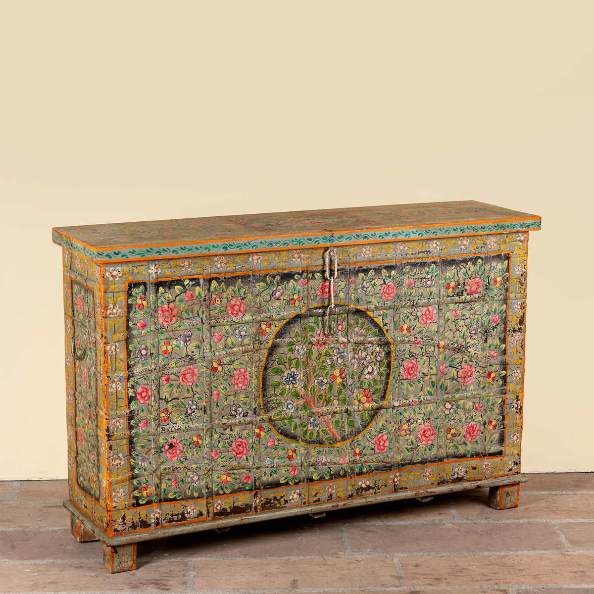 Side angle image of a Armaan hand painted reclaimed teak wood storage chest with colourful floral motifs and traditional iron fittings, 151cm wide