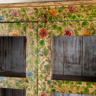 Close up image image of a hand-painted reclaimed wood showcase cabinet with floral motifs and glass doors, sustainable furniture and vintage home decor style, 96 × 40 × 182 cm.