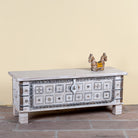 Side angle image of a Aryav whitewashed mango wood coffee table chest with decorative iron fittings 116cm