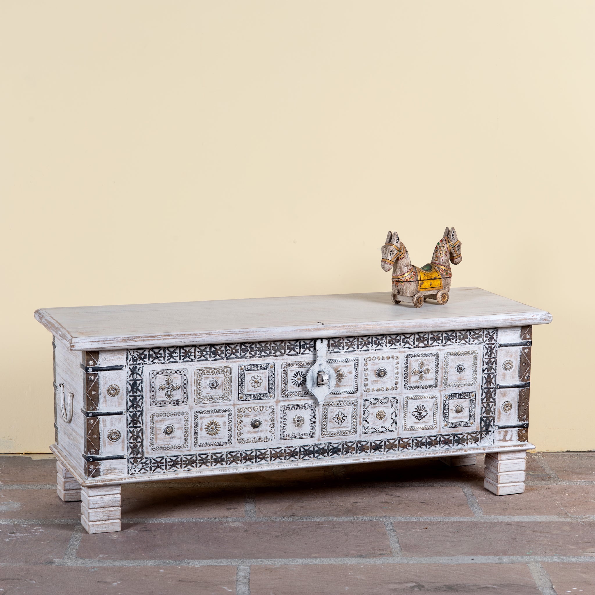Side angle image of a Aryav whitewashed mango wood coffee table chest with decorative iron fittings 116cm