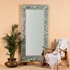 Carved mango wood mirror Apsara blue in distressed turquoise finish with intricate hand‑carved floral details. A unique piece of Indian furniture online ideal for vintage home decor and boho interiors.
