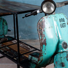 Close up image of a house bar crafted from a full vintage Indian Bajaj scooter with industrial metal frame and wooden shelves, featuring original patina and retro design elements.

