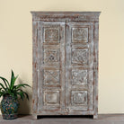 Reclaimed teak wood cabinet Atharva with floral hand-carved doors in a vintage distressed finish. A sustainable furniture piece ideal for rustic and character-rich living room interiors.