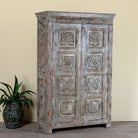 Side angle image of a reclaimed teak wood cabinet Atharva with floral hand-carved doors in a vintage distressed finish. A sustainable furniture piece ideal for rustic and character-rich living room interiors.