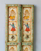 Close up image of a Aum hand-painted teak door panel featuring Goddess Lakshmi and traditional dancers, framed by leafy green carvings—a spiritual and unique Indian wall decoration repurposed from antique teak architecture.