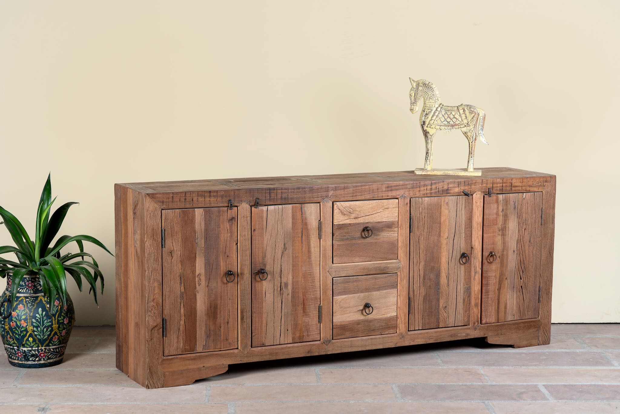Side angle image of a reclaimed wood sideboard Avana in a rustic minimalistic style with multiple cabinets and drawers, showcasing natural wood grain and simple iron handles.