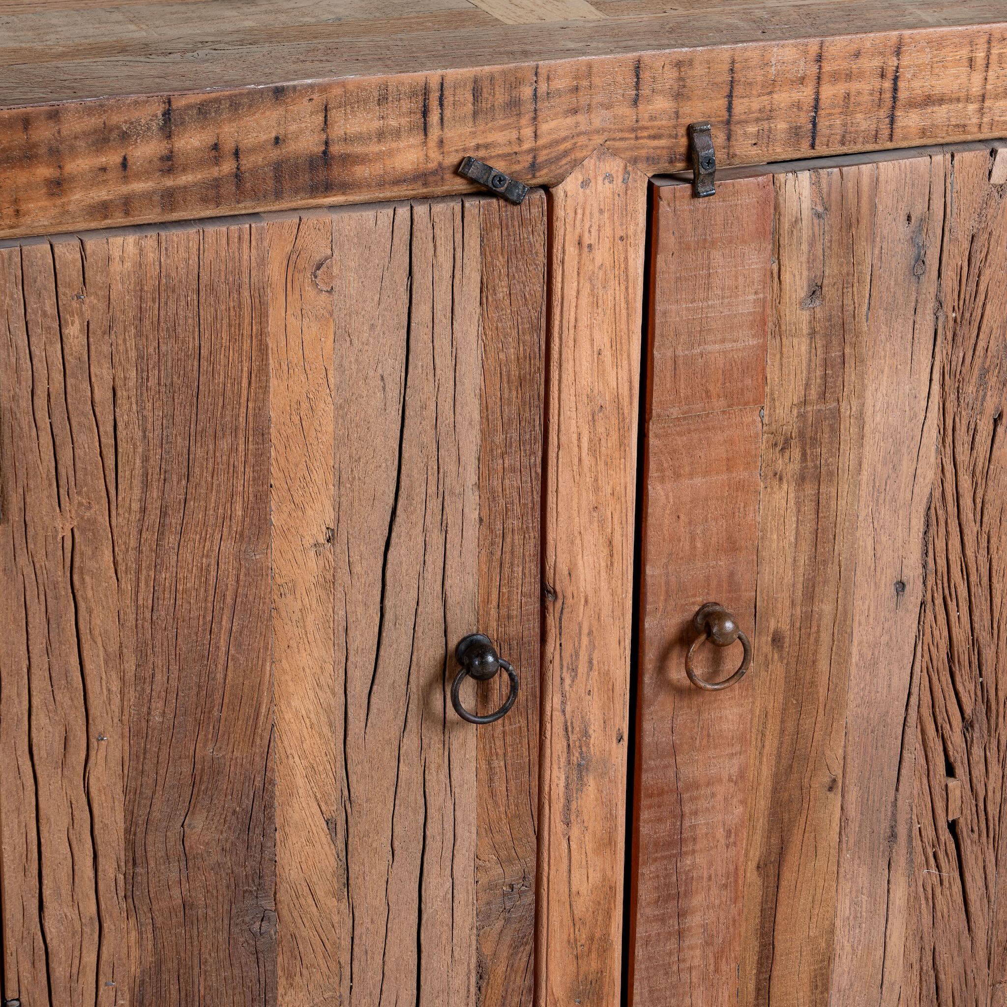 Close up image of a reclaimed wood sideboard Avana in a rustic minimalistic style with multiple cabinets and drawers, showcasing natural wood grain and simple iron handles.