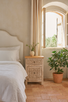 Life style image of a pair of vintage night stands in mango wood with hand-carved geometric details and distressed finish; ideal for vintage home decor, 76 × 56 × 35 cm.