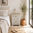 Life style image of a vintage night stand made of natural mango wood with hand-carved geometric details and distressed finish; ideal for vintage home decor, 76 × 56 × 35 cm.