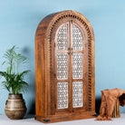 Side angle image of a handcrafted carved wooden wardrobe in half-round design with whitewashed lattice panels – bedroom furniture with Mediterranean flair and artistic detail.