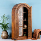 Side angle image with open doors of a handcrafted carved wooden wardrobe in half-round design with whitewashed lattice panels – bedroom furniture with Mediterranean flair and artistic detail.