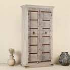 Side angle image of a old door cabinet with reclaimed teak doors, floral carvings, and iron accents; artisan teak wood wardrobe with mango wood frame, 100 × 44 × 206 cm.